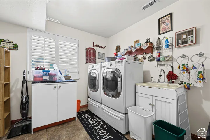 Laundry room with window, white cabinetry, built-in utility sink, and tile flooring