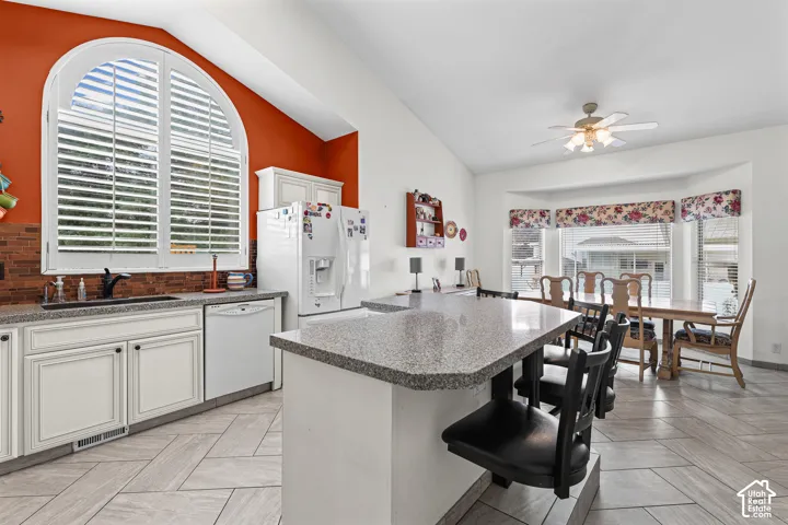 Kitchen featuring white cabinetry, granite-finish countertops, and a large arched window with plantation shutters