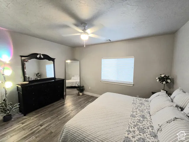 Wood-finish flooring, ceiling fan, and window with blinds