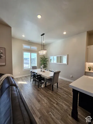 Wood-finish flooring, recessed ceiling lighting, decorative chandelier, and plantation-style window coverings