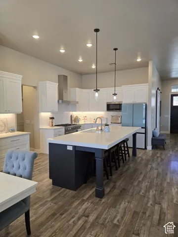 Spacious kitchen featuring an extended island with seating, white shaker cabinetry, stainless steel appliances, and recessed lighting