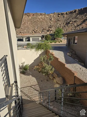 Terraced xeriscape landscaping featuring a rock garden, concrete block retaining wall, and metal stair railing