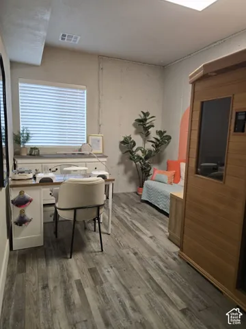 Wood-finish flooring throughout, recessed ceiling lighting, a built-in bench with storage, and a single window with blinds