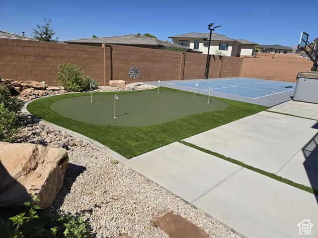 Backyard featuring a putting green, multi-sport court, and concrete patio