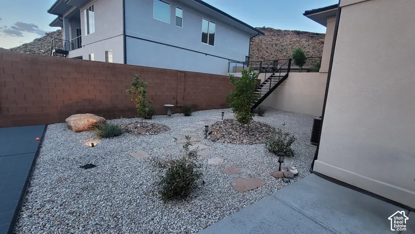 Low-maintenance landscaping featuring gravel ground cover, mature plantings, large decorative boulders, and stepping stone pathways