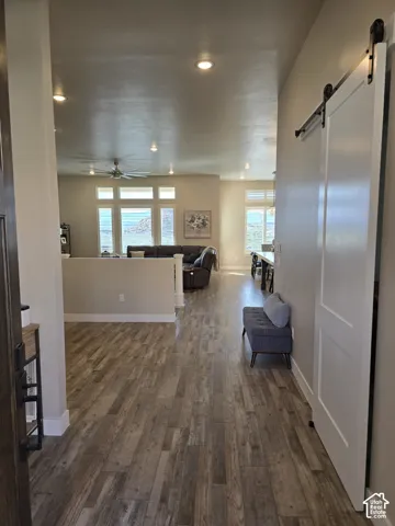 Wood-finish flooring throughout, featuring recessed lighting and a ceiling fan