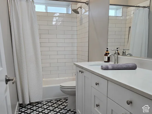 Patterned floor tile, white subway tile shower surround, white vanity cabinetry, light-toned countertop, and recessed lighting