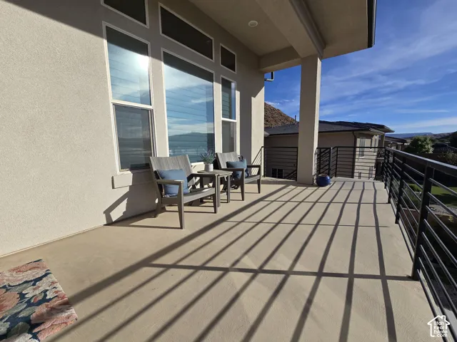 Expansive balcony featuring a stucco exterior, multiple large windows, a sturdy support column, and contemporary metal railings