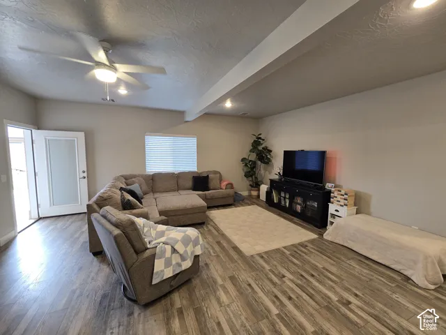 Spacious living area featuring wood-finish flooring, recessed lighting, and a ceiling fan with integrated light