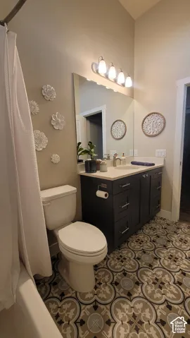 Patterned floor tile, single vanity with dark cabinetry, integrated countertop, and a shower/tub combination