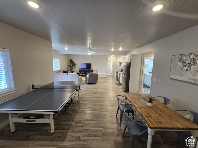 Open-concept living area featuring wood-finish flooring, recessed lighting, and a dining space with a natural wood table