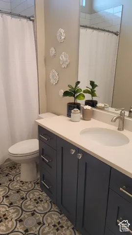 Bathroom featuring a patterned floor tile, blue vanity cabinetry, a white countertop, and a shower with subway tile surround