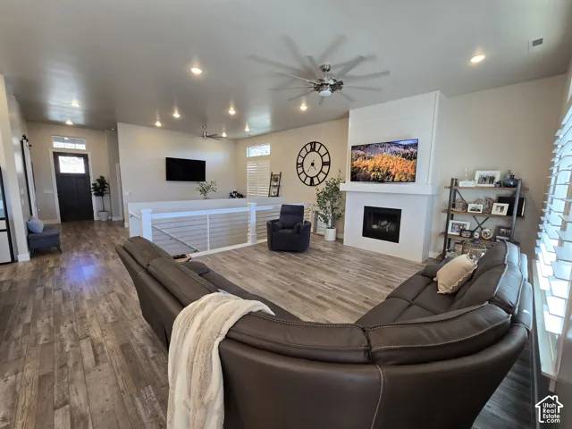 Living area featuring wood-finish flooring, a contemporary fireplace with shiplap accent, recessed lighting, and a ceiling fan