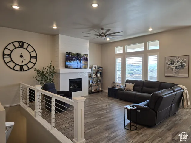 Recessed lighting, wood-finish flooring, and a modern fireplace with a tiled surround
