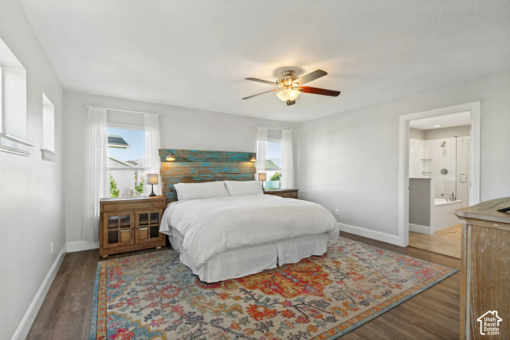 Primary bedroom with LVP flooring, multiple windows for great natural light and a ceiling fan with integrated lighting