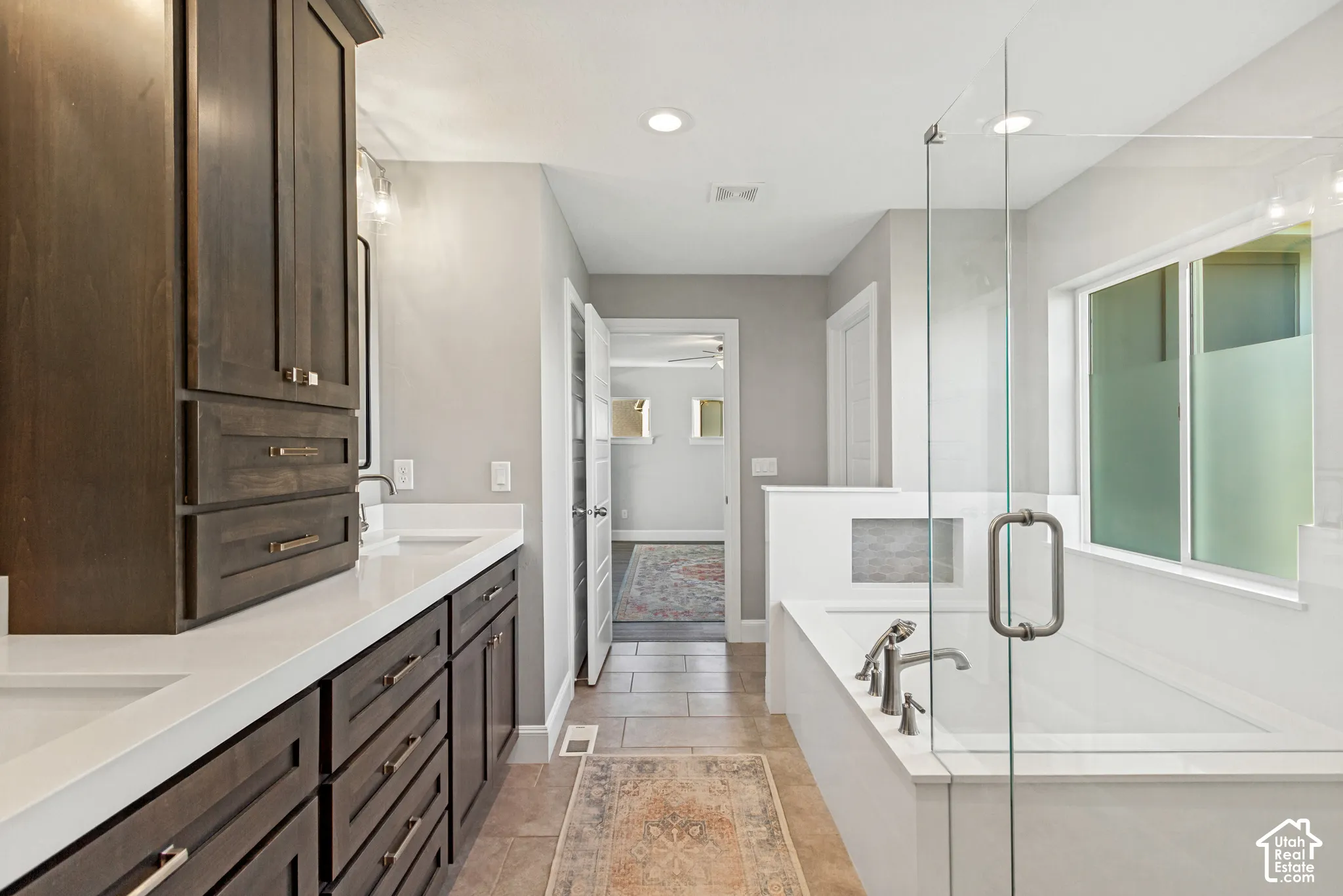 Primary bath with wonderful natural light, dual-sink vanity with custom dark-wood shaker style cabinetry, white quartz countertop, rectangular undermounted sinks, and contemporary recessed medicine cabinets, separate generously sized soaking tub and showe