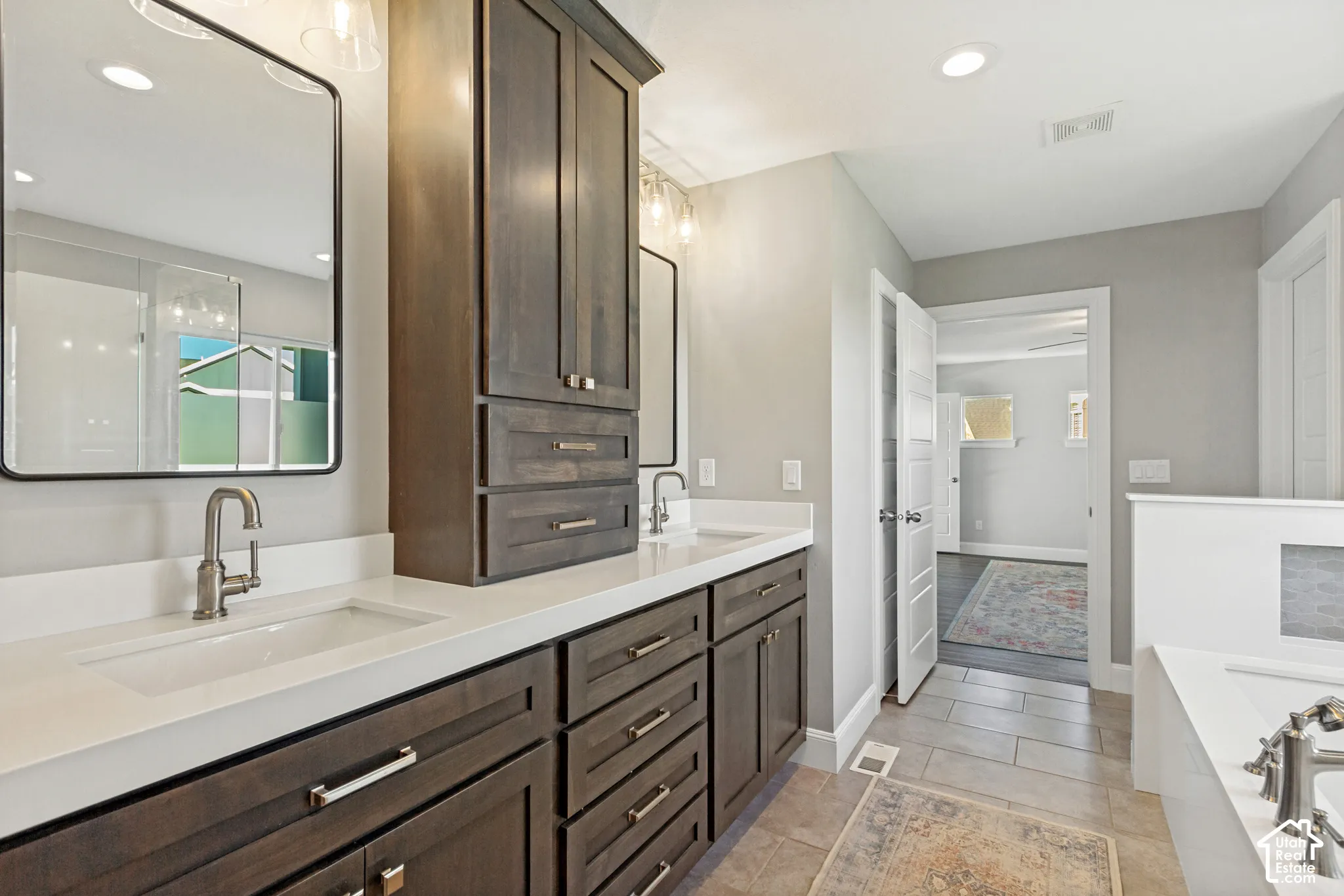 Primary bath with wonderful natural light, dual-sink vanity with custom dark-wood shaker style cabinetry, white quartz countertop, rectangular undermounted sinks, and contemporary recessed medicine cabinets, separate generously sized soaking tub and showe