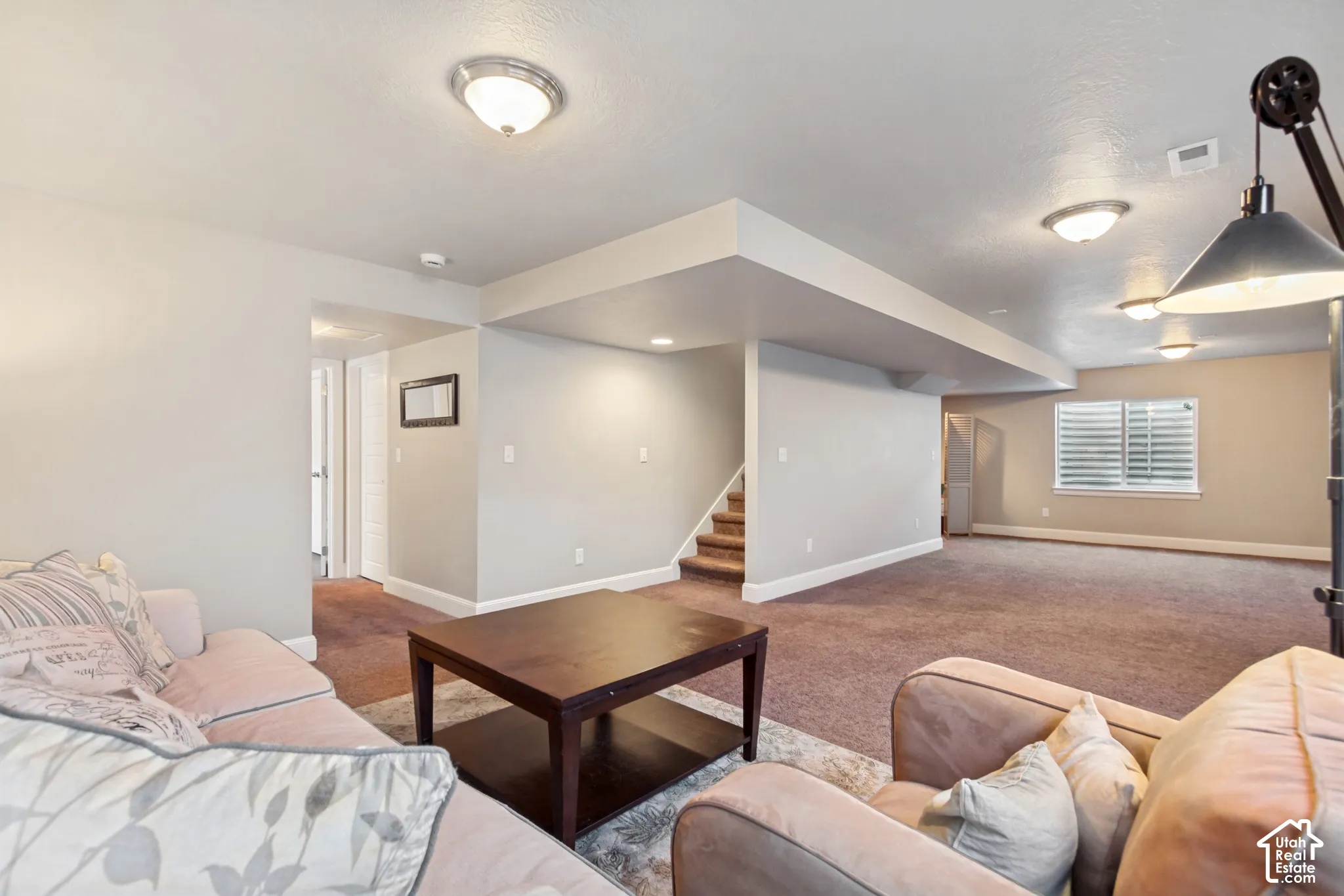 Open-concept basement perfect for entertaining featuring carpeted flooring, built-in projection screen and prewired for a home theater and plumbed foir a wet bar, multiple egress windows with window wells provide plenty of light