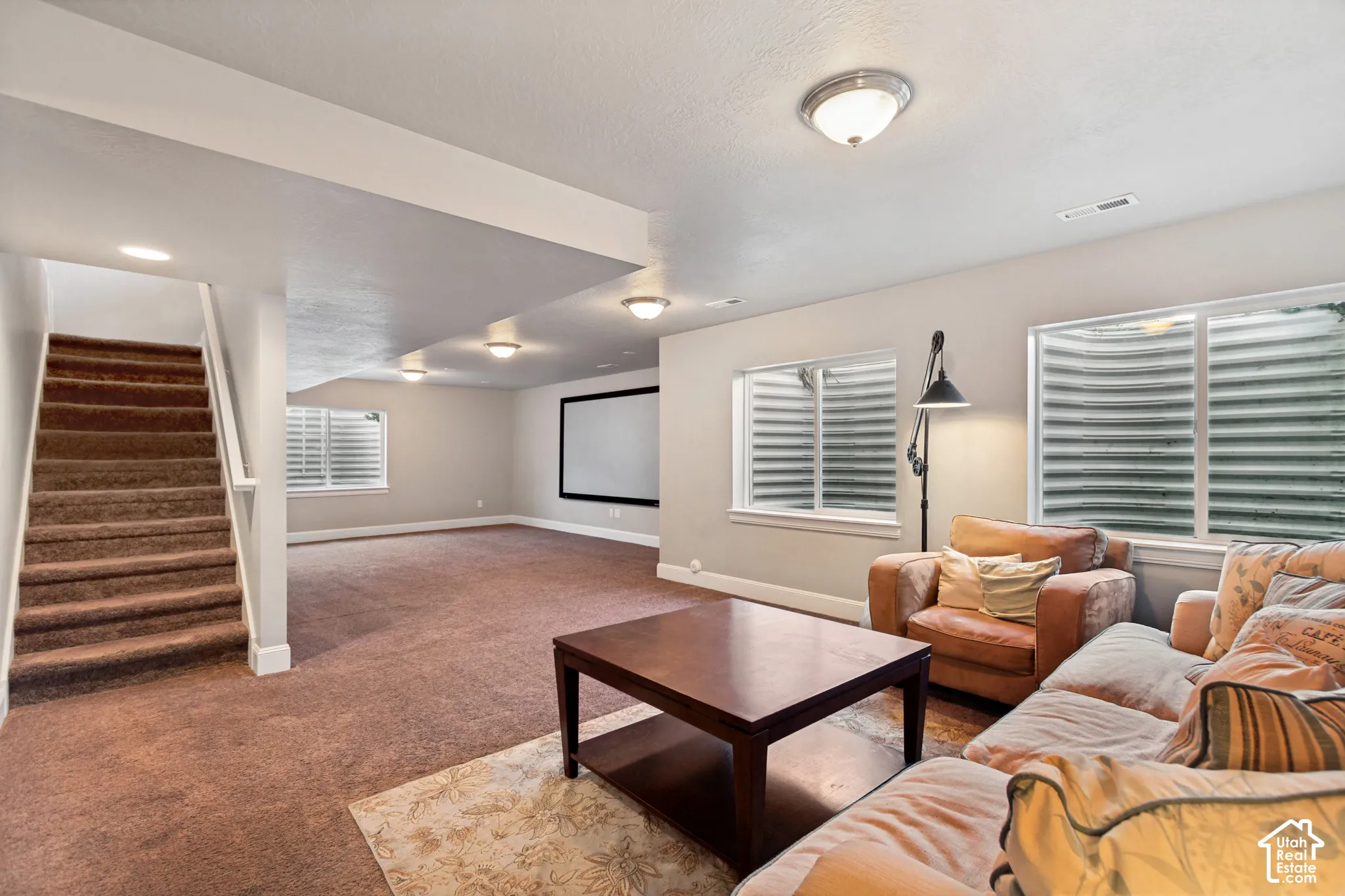 Open-concept basement perfect for entertaining featuring carpeted flooring, built-in projection screen and prewired for a home theater and plumbed foir a wet bar, multiple egress windows with window wells provide plenty of light