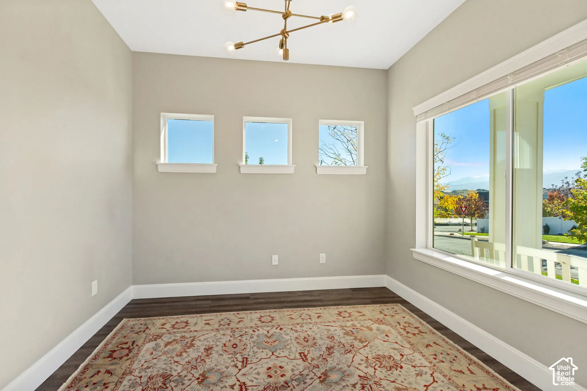Inviting office space featuring LVP flooring, a modern multi-arm chandelier, three square accent windows, and a large picture window providing excellent natural light and glass double door entry