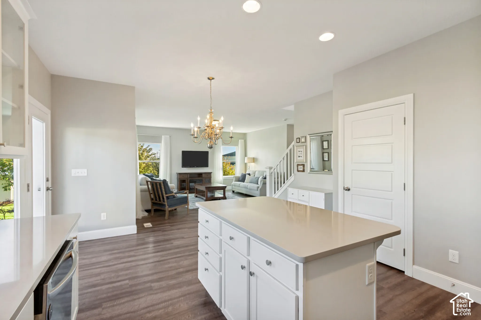 Kitchen featuring wonderful natural light, white shaker-style cabinetry with glass-front display uppers, expansive center island, quartz countertops, stainless steel appliances, and LVP flooring