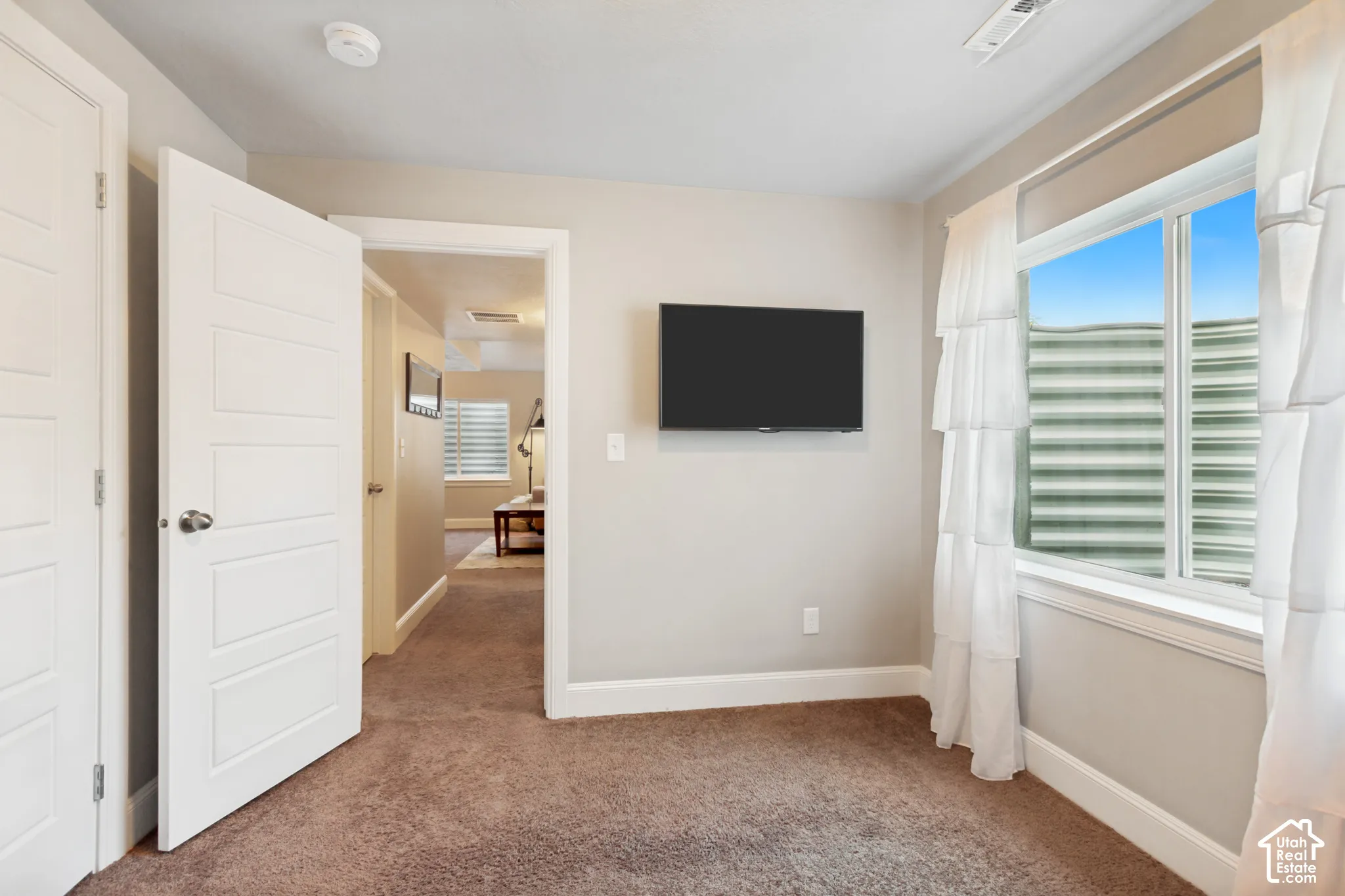 carpeting, an egress window with a metal window well, and plenty of natural light and a generously sized closet