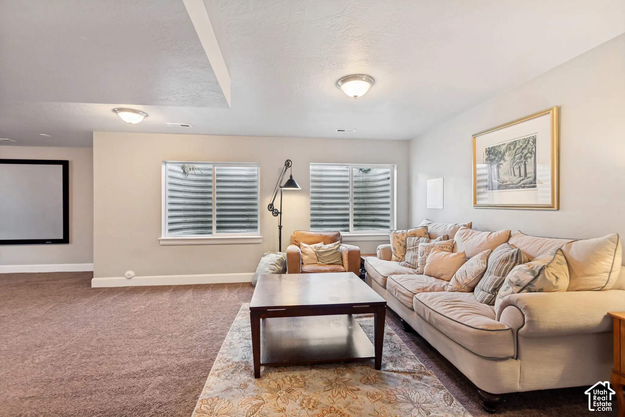 Open-concept basement perfect for entertaining featuring carpeted flooring, built-in projection screen and prewired for a home theater and plumbed foir a wet bar, multiple egress windows with window wells provide plenty of light