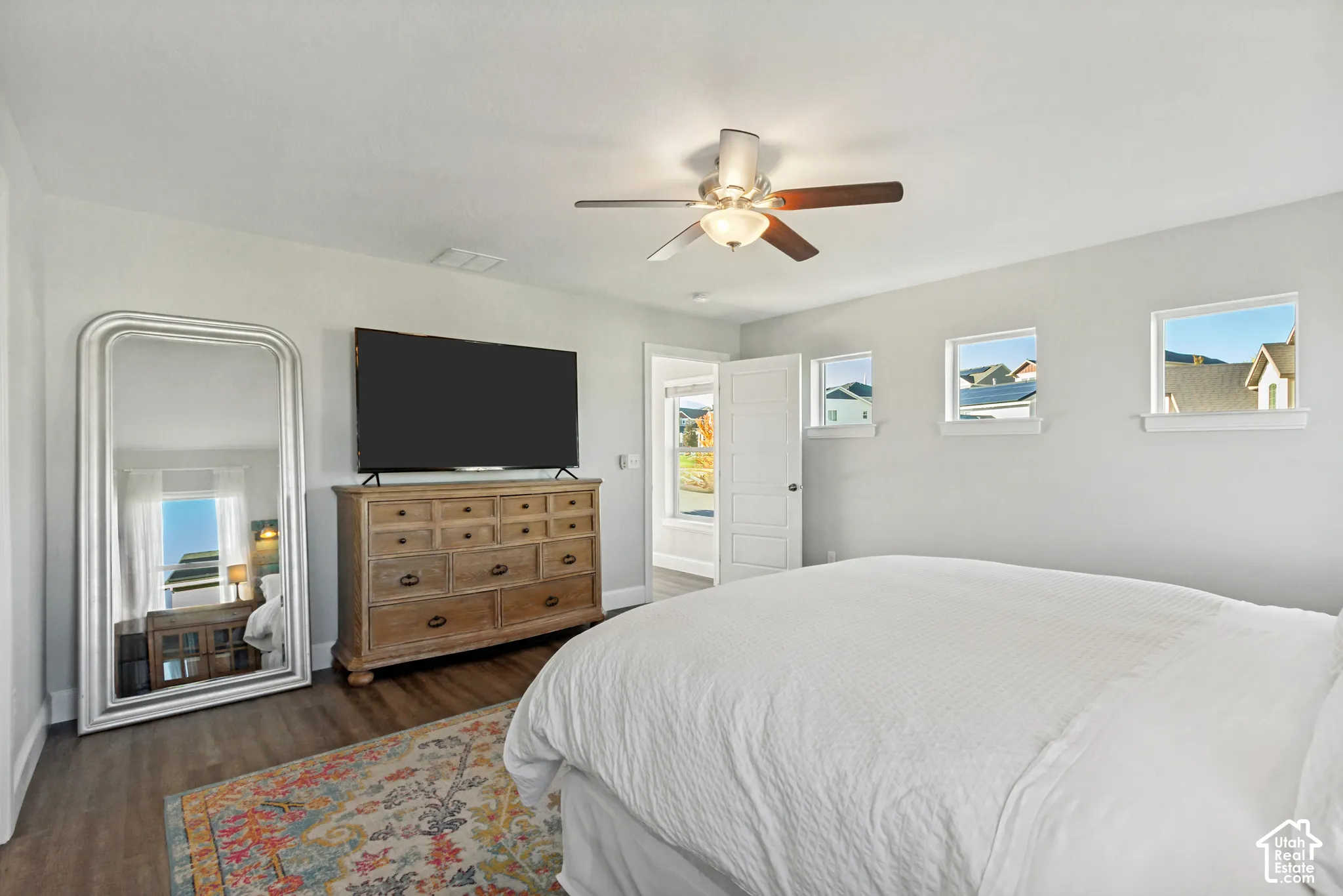 Primary bedroom with LVP flooring, multiple windows for great natural light and a ceiling fan with integrated lighting