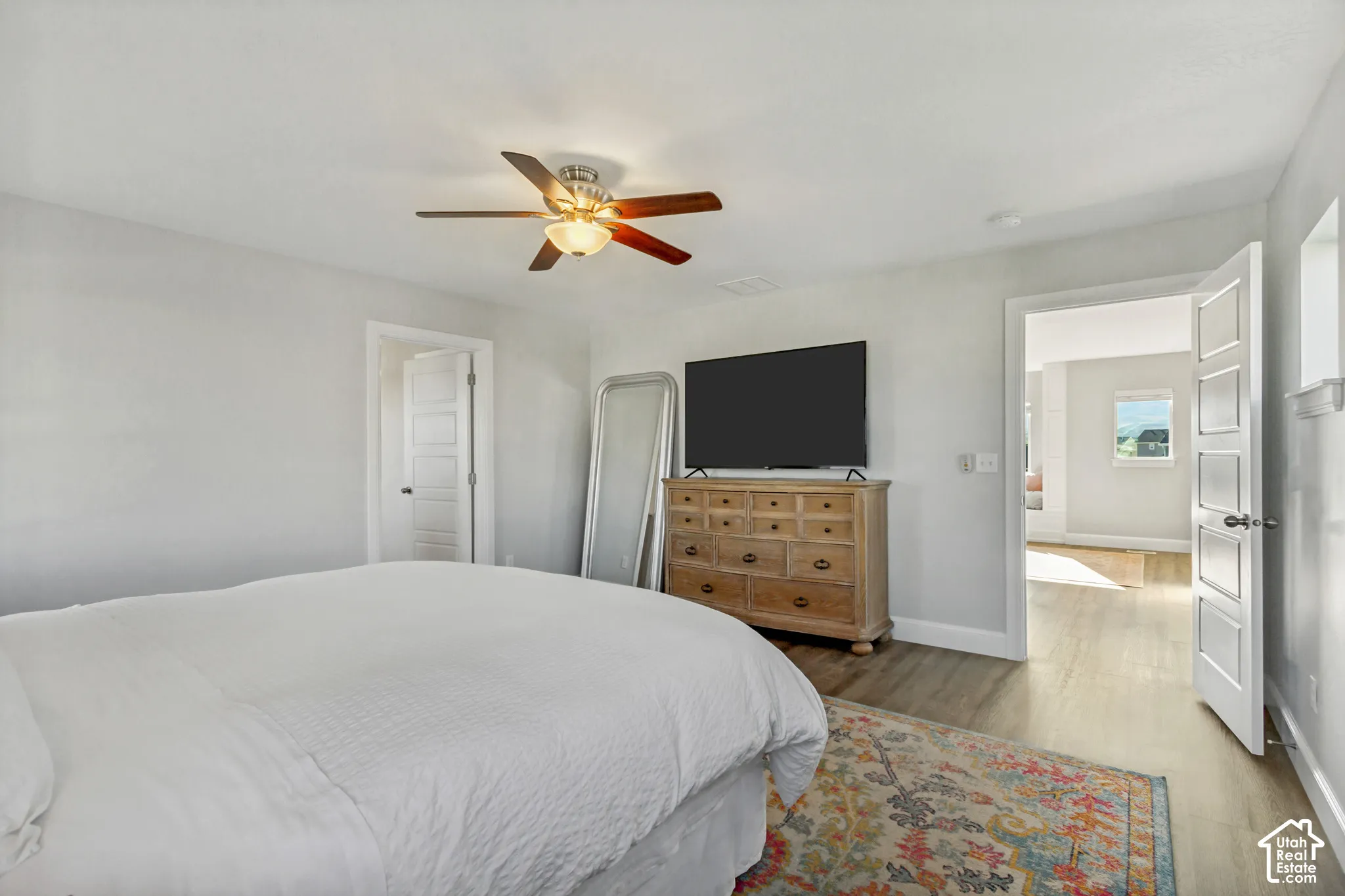 Primary bedroom with LVP flooring, multiple windows for great natural light and a ceiling fan with integrated lighting