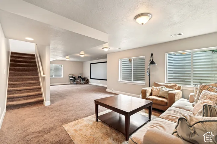 Open concept basement living and entertaining area with natural light, prewired for home theater with a large projector screen