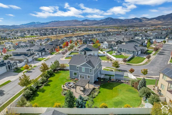Two-story residence featuring a gray siding exterior, an attached pergola, stone-paver hardscaping, a fully fenced backyard, and a mountain backdrop