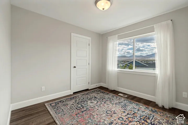 Soft gray wall paint, wood-finish flooring, white trim, and a window with mountain scenery