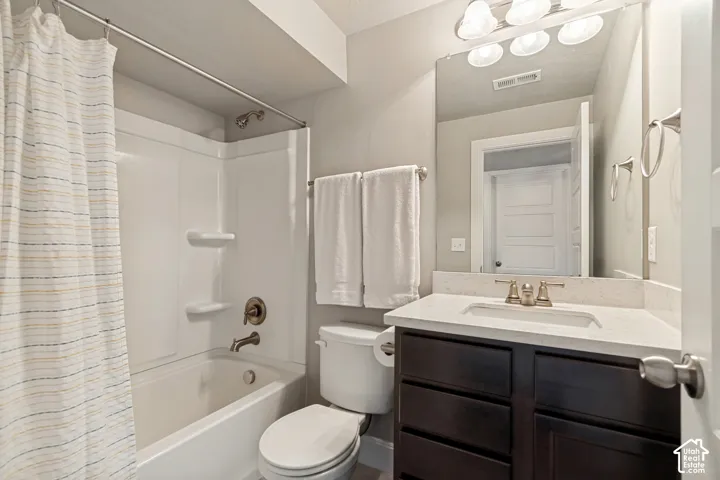 Tub/shower combination with a single-handle faucet, dark wood-finish vanity with a light-colored countertop, and a vanity mirror with overhead lighting
