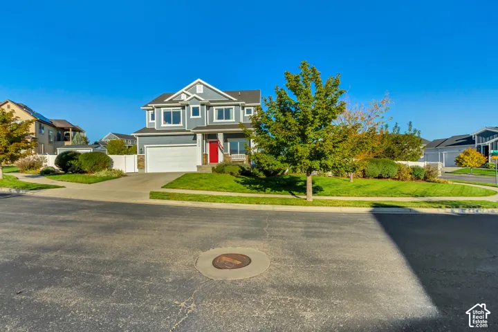 Two-story residence featuring full wrap gray James Hardie cement board siding with stone veneer accents, a covered front porch, a red entry door, and a two-car garage