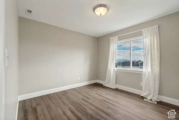 Wood-finish flooring with white baseboards, a semi-flush mount ceiling light, and a window with white trim