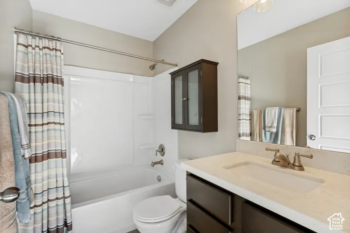 Bathroom featuring a light-toned solid surface vanity countertop with an integrated rectangular sink, dark wood-finish cabinetry, a large wall-mounted mirror, and a full-height shower and tub surround