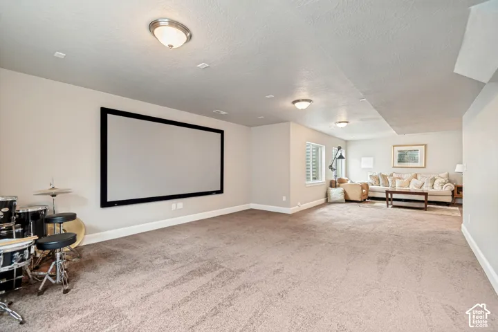 Open concept basement living and entertaining area with natural light, prewired for home theater with a large projector screen