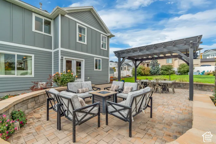 Expansive paver patio with a built-in stone retaining wall, Western Timber Frame pergola, and a grassy lawn area