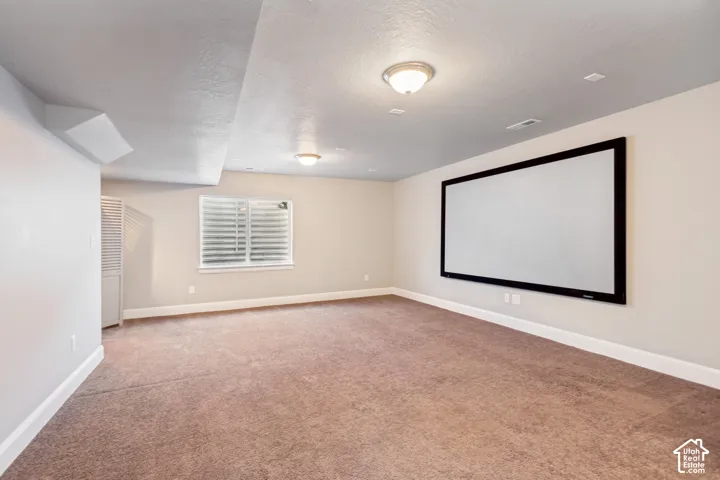 Open-concept basement perfect for entertaining featuring carpeted flooring, built-in projection screen and prewired for a home theater and plumbed foir a wet bar, multiple egress windows with window wells provide plenty of light