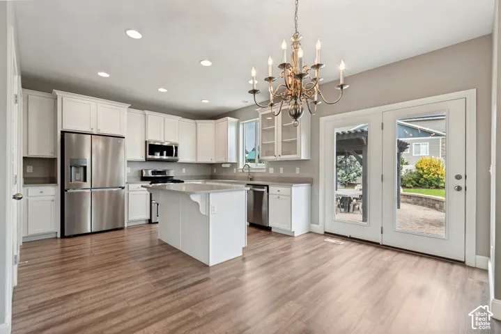 Open kitchen concept featuring white cabinetry, stainless steel appliances, a central island and quartz countertops