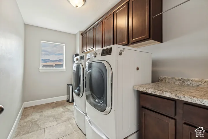 Laundry area featuring dark-stained wood cabinetry, a laundry sink, tiled flooring, and a window with mountain scenery