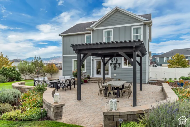 Paver patio featuring a Western Timber Frame pergola, built-in stone retaining walls, and a manicured lawn