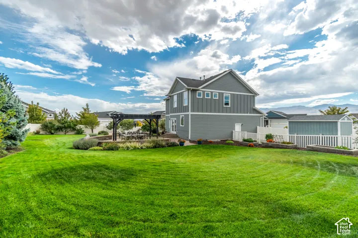 Expansive green lawn with a paver patio and dark wood pergola