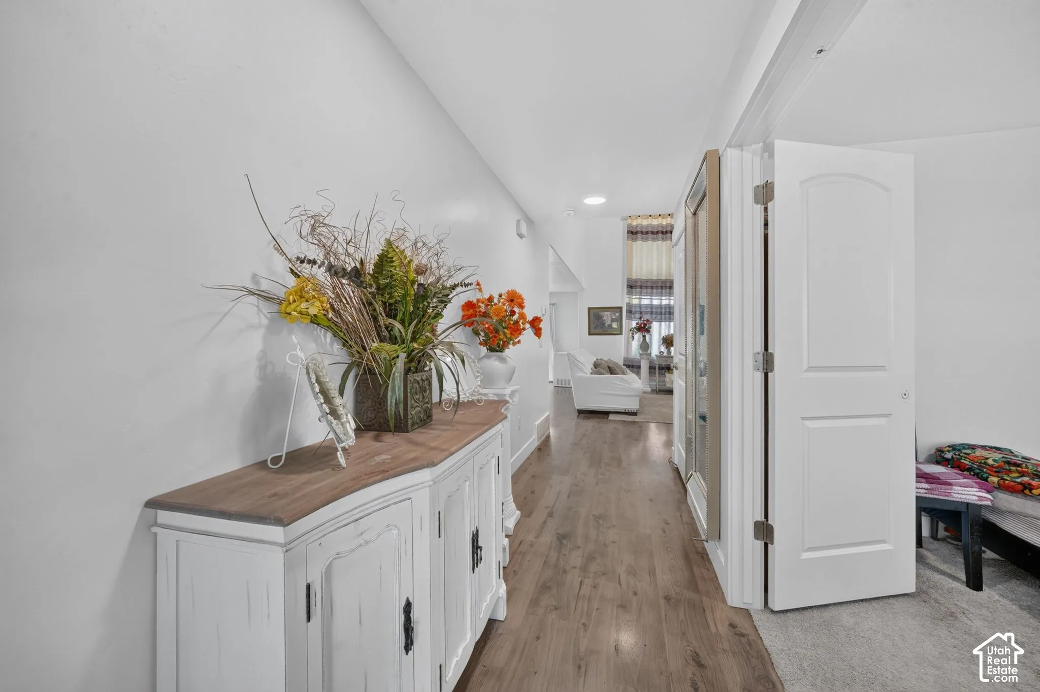 Hallway with wood-finish flooring, recessed lighting, and a white interior door