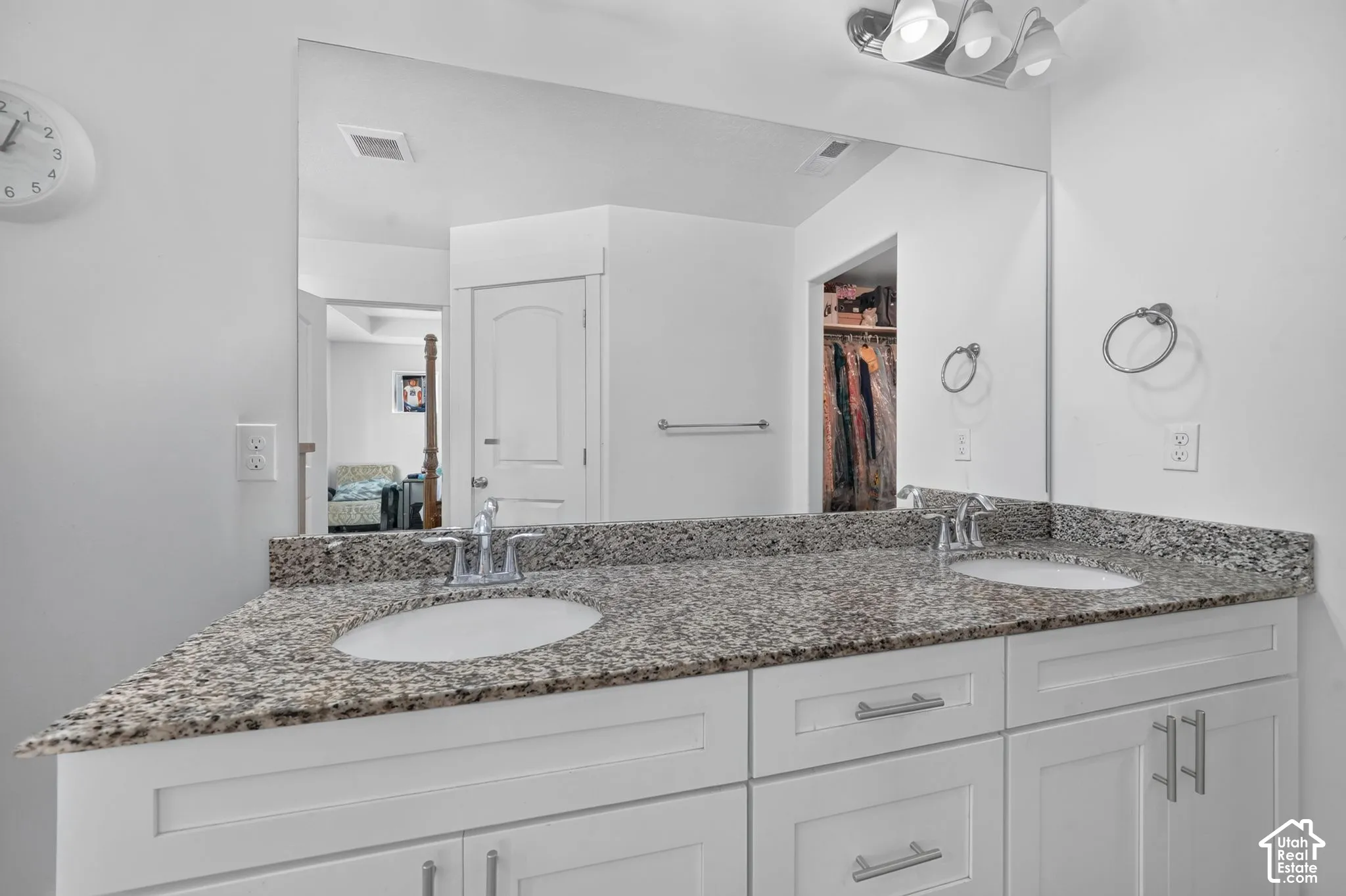 Spa-inspired master bath featuring dual vanities with brushed nickel hardware, extensive granite countertops, and a large framed mirror with integrated lighting
