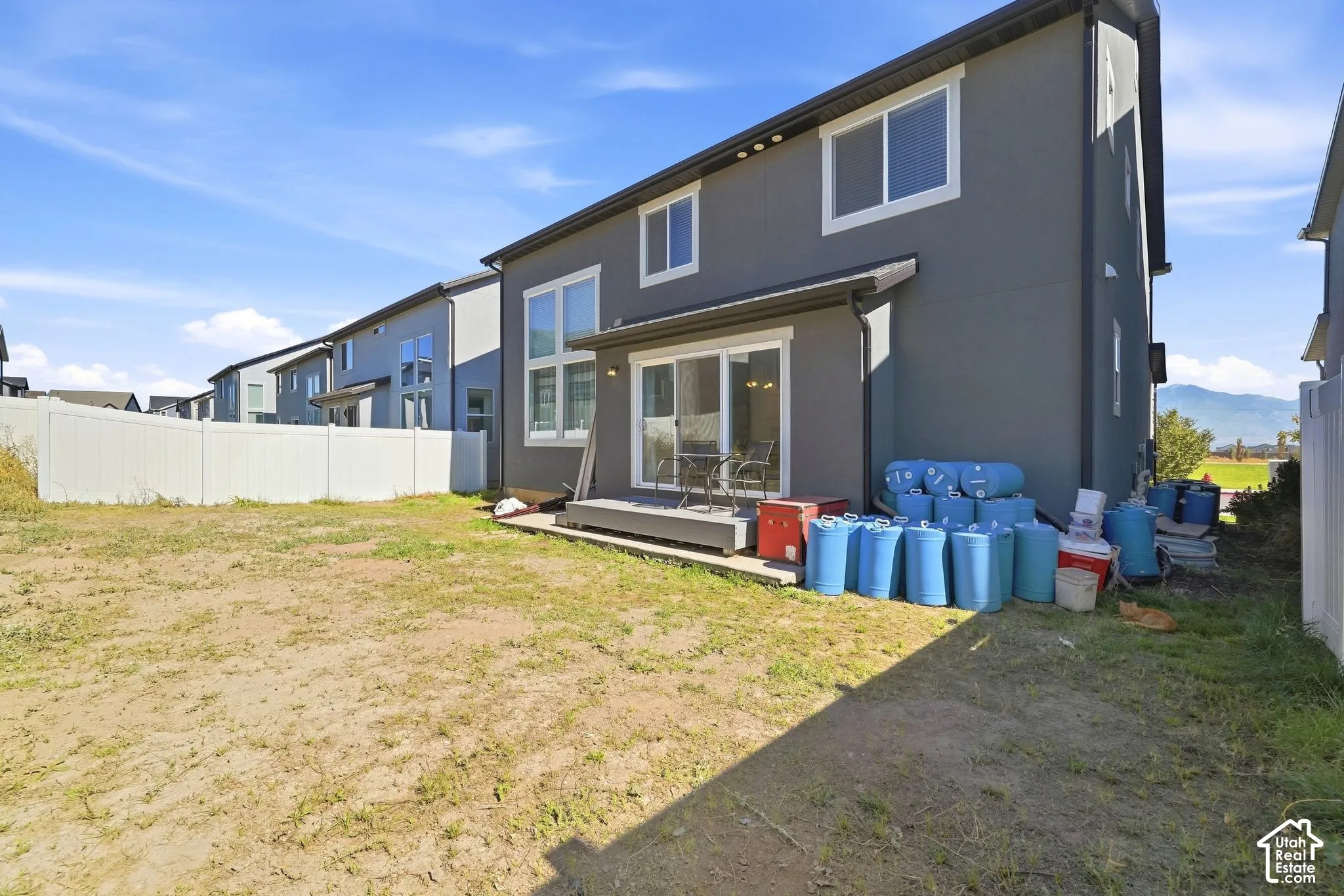 Rear exterior featuring a sliding glass door, elevated deck, and white vinyl fencing