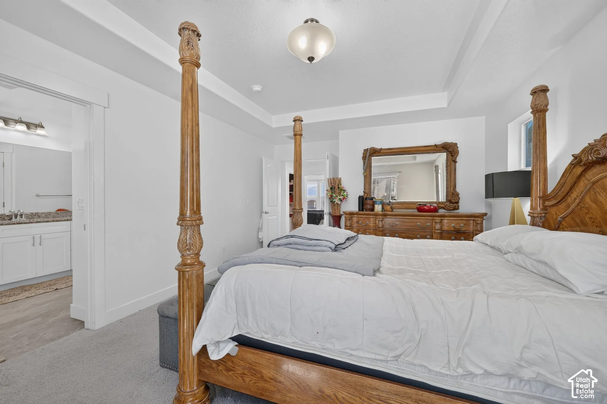 Tray ceiling, recessed lighting, carpet flooring, window with natural light, vanity with dual sinks, and granite-style countertop