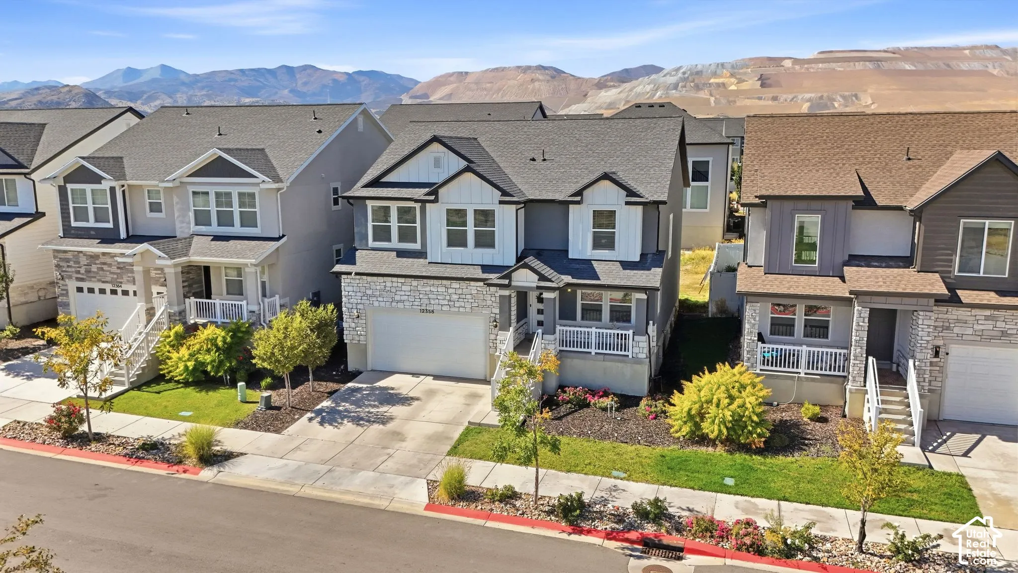 Two-story residence featuring a gray and cream exterior with multiple gabled rooflines, white-trimmed windows, and an attached two-car garage
