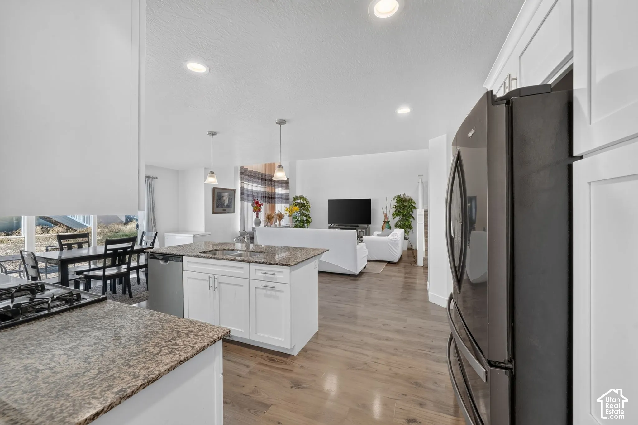 Kitchen featuring granite countertops, a built-in dishwasher, and a center island with pendant lighting