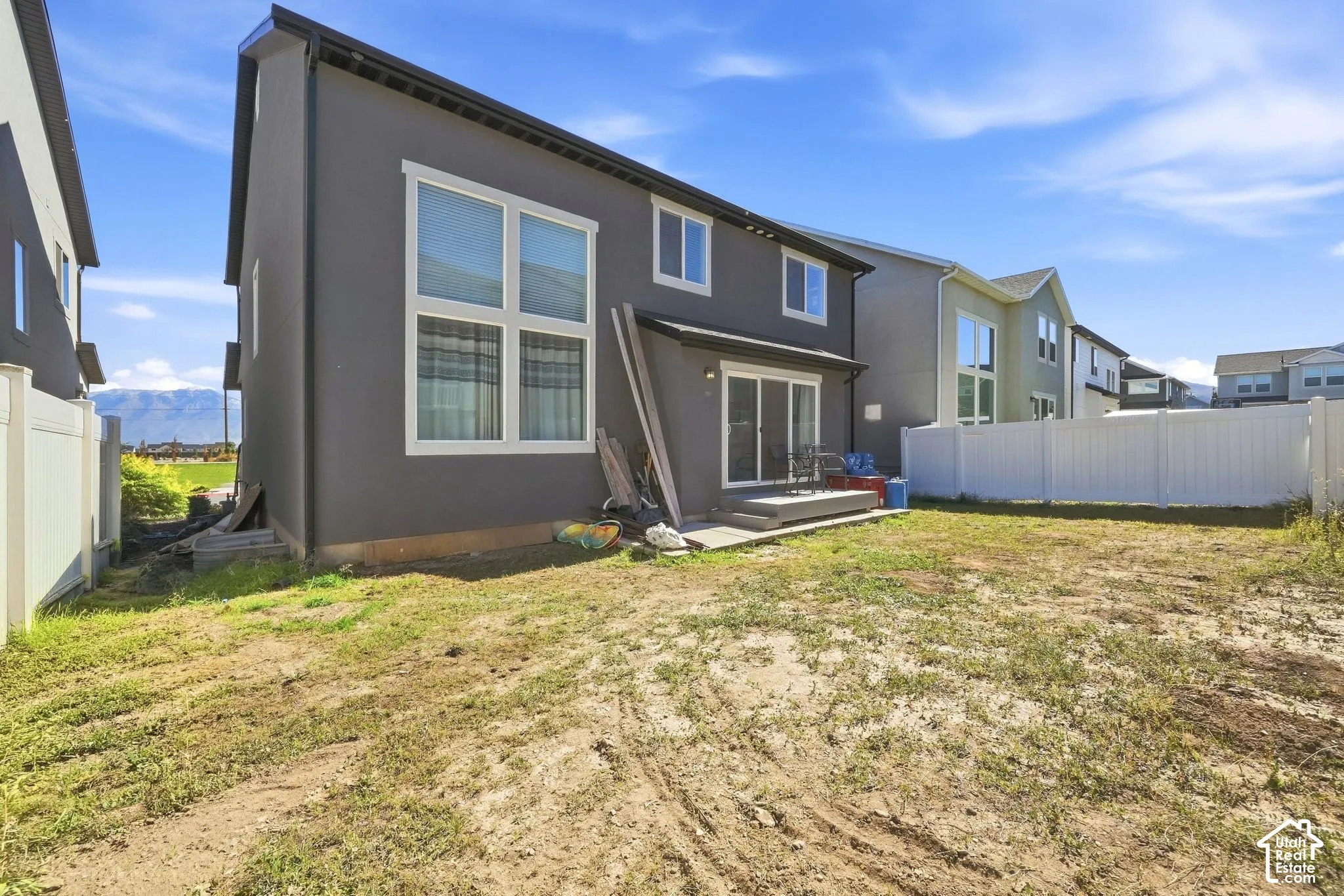 Exterior featuring dark-toned siding, white-framed windows, and a concrete patio